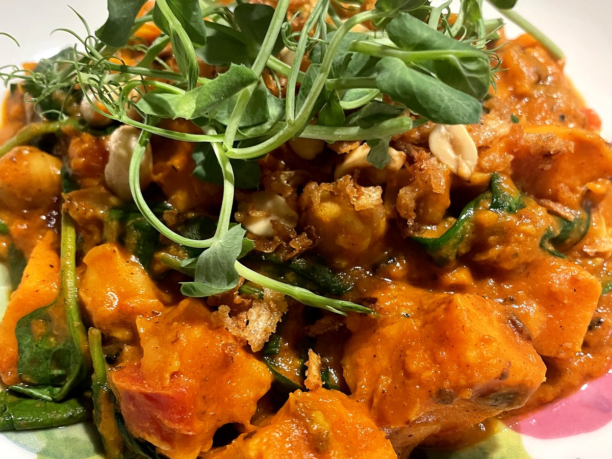 Creamy West African peanut stew with sweet potato, spinach and pea shoots